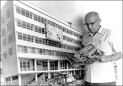 Adolfo Aizen, na década de 70, em frente a uma foto ampliada da Ebal, quando já se dedicava mais aos livros infantis. Note o sugestivo nome do exemplar nas mãos do editor. Cortesia da família Aizen.